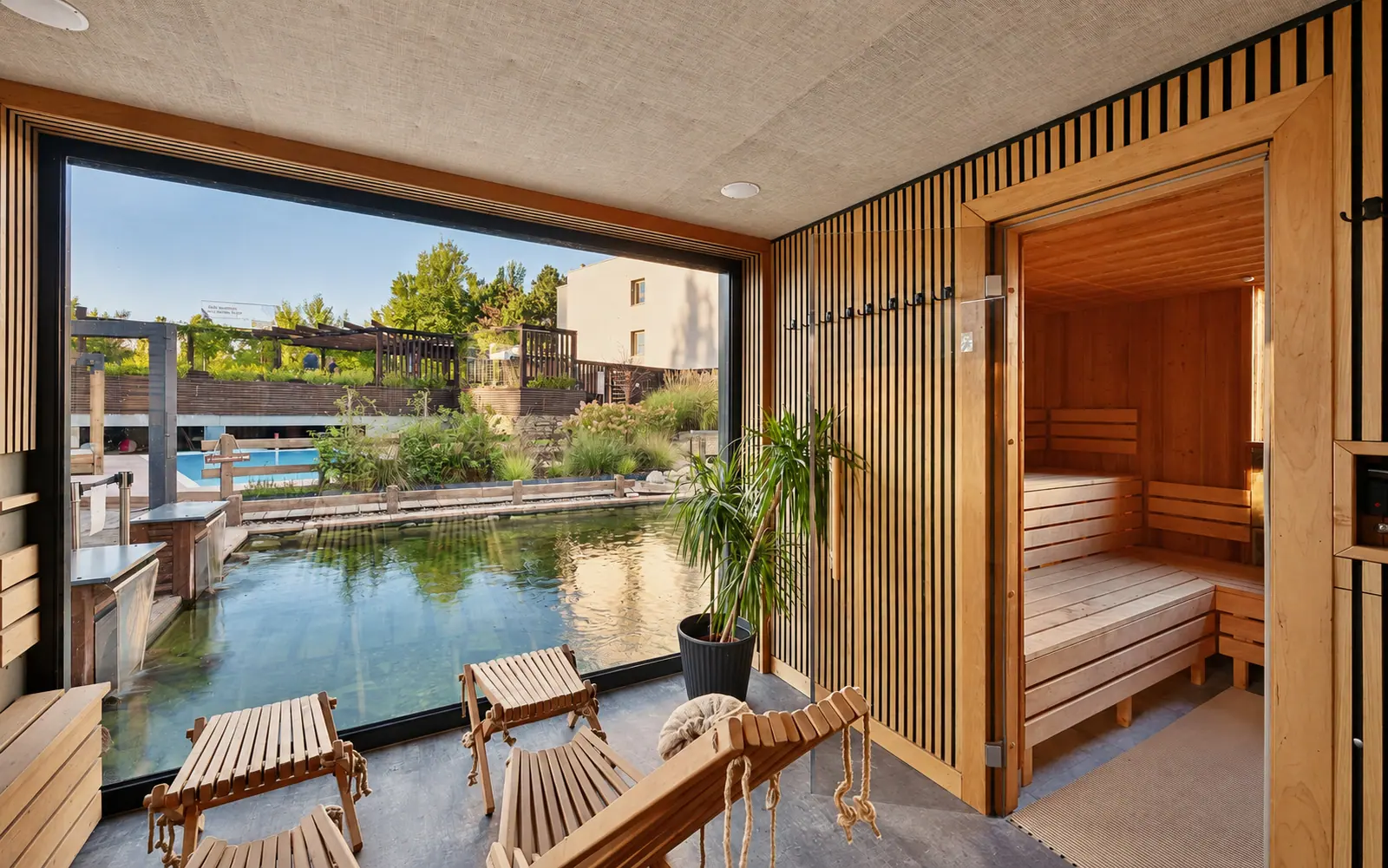 Lounge s pohovkou, dřevěnými stoly a prosklenou stěnou do zahrady