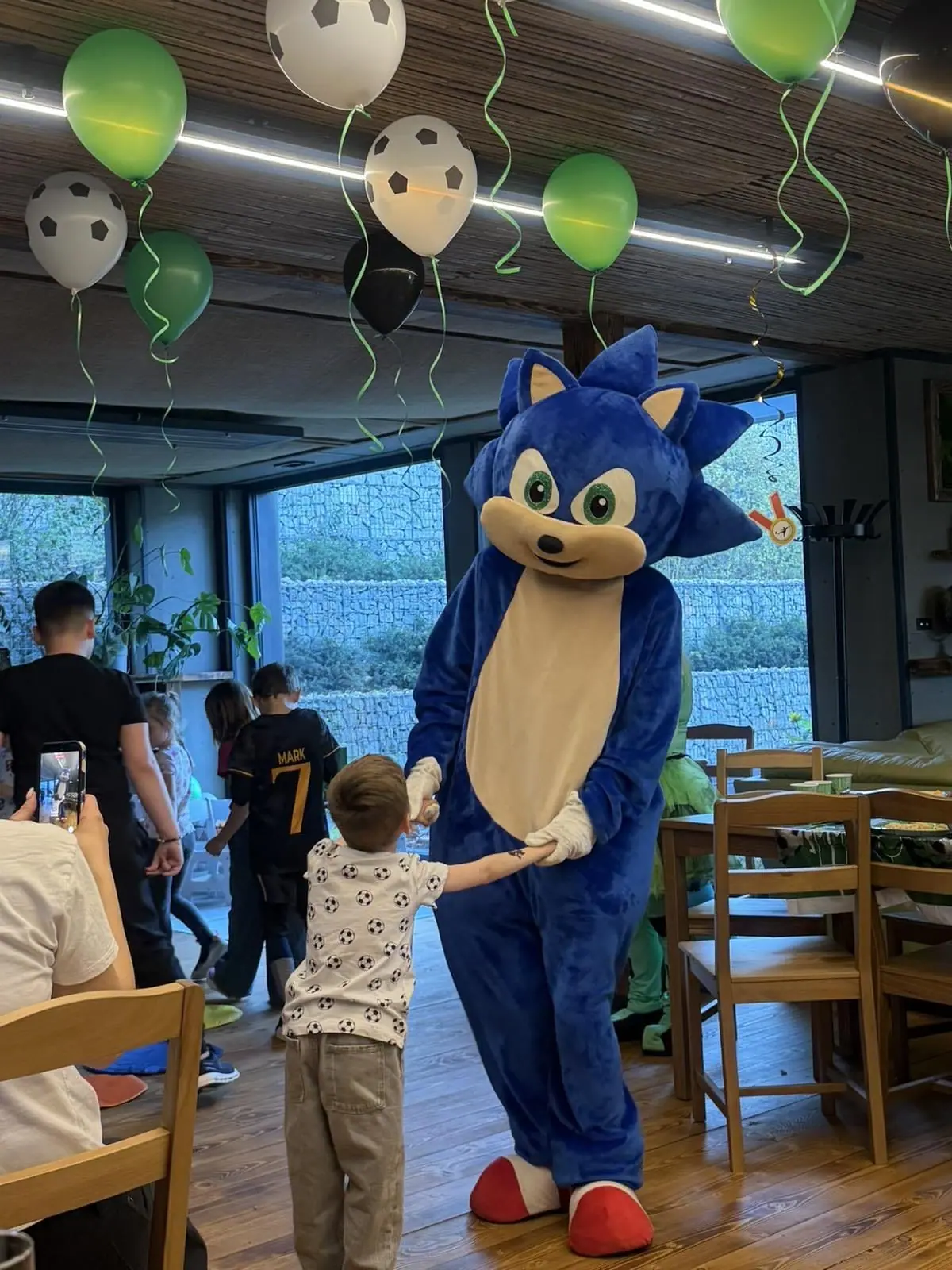 Maskot v kostýmu vítá dítě mezi balónky